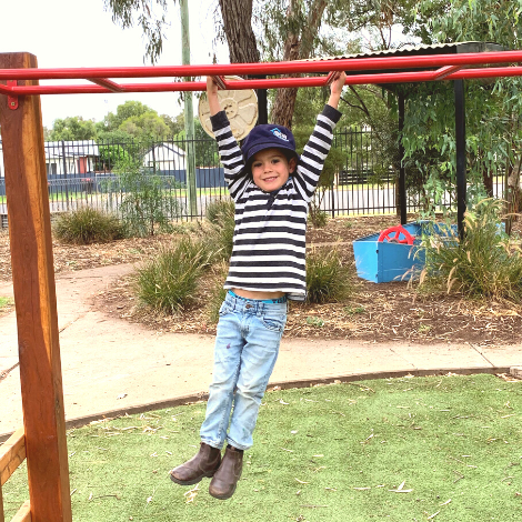 Young person on playground monkey bars, swinging across.